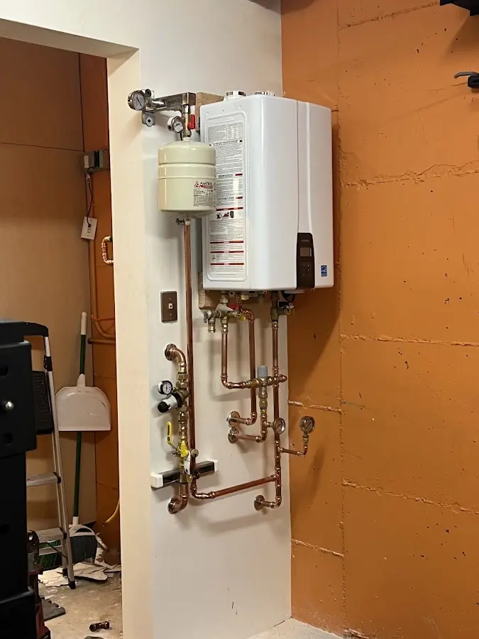 Plumbing technician inspecting water heater connections in Pembroke